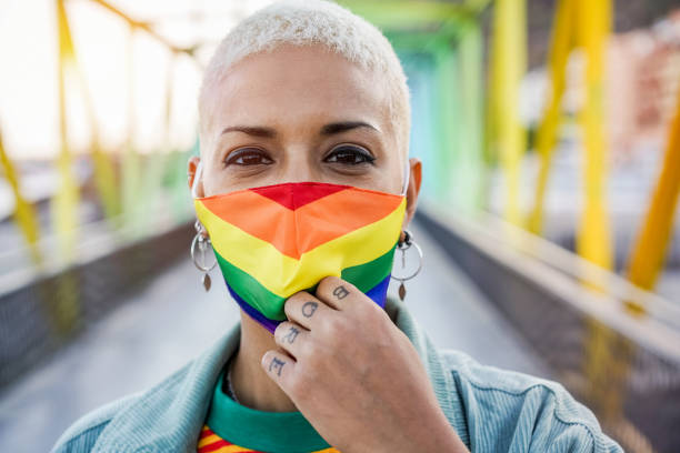 young woman wearing gay pride mask - lgbt rights, diversity, tolerance and gender identity concept - life events laughing women latin american and hispanic ethnicity imagens e fotografias de stock