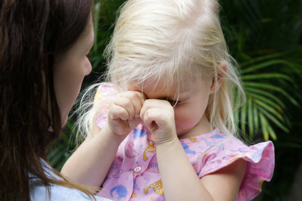 giovane madre che abbraccia la figlia piccola che piange. figlia triste tra le braccia di sua madre. - pensive only baby girls baby girls baby foto e immagini stock