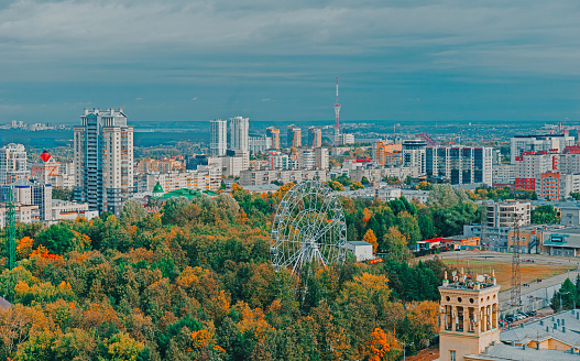 View of the central park of Perm from a height. Ferris wheel among green trees. City skyline.