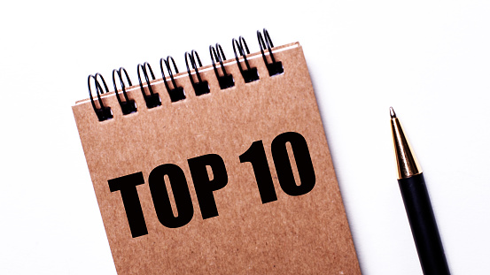 TOP-10 written on a brown notebook next to a black pen on a light background
