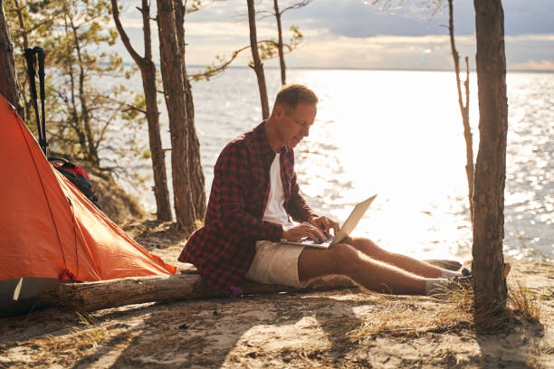 istock Cheerful man using laptop during camping in nature 1277757862