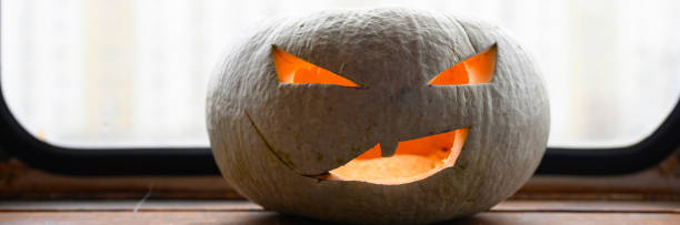 istock glowing spooky Halloween pumpkin at home on the table. banner 1277760236