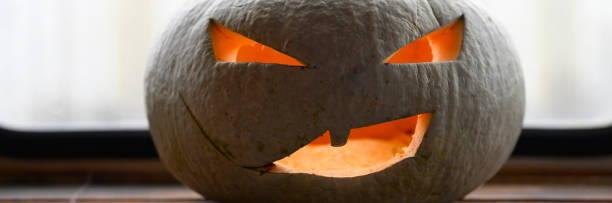 istock glowing spooky Halloween pumpkin at home on the table. banner 1277760308