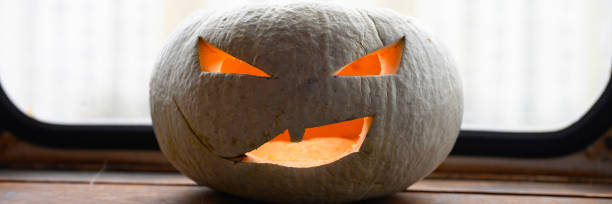 istock glowing spooky Halloween pumpkin at home on the table. banner 1277760338