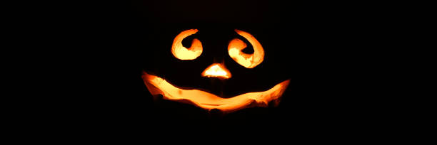 glowing smiling face Halloween pumpkin, candle holder, isolated on night dark black background. banner