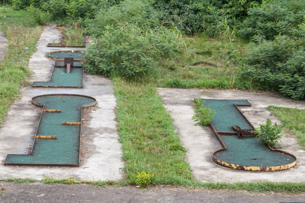 Mini golf course lane with obstacles and hole on bright green turf. Horizontal image with copy space ideal for banners advertising family leisure and sports content no people. Team building mini golf corporate outdoor activity
