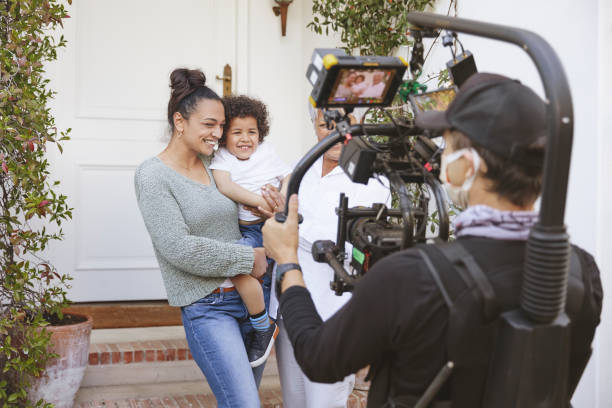 backstage with happy multigeneration family Portrait of happy mother holding her son together with grandma and being filmed by professional videographer holding camera on easy rig and wearing a face mask. film set stock pictures, royalty-free photos & images