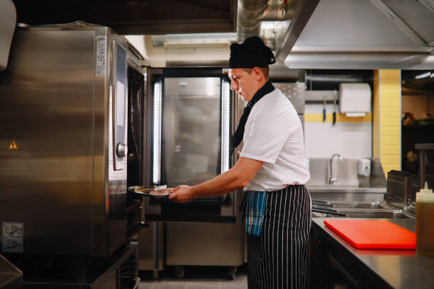 istock Restaurant cook putting food in the oven 1277763123