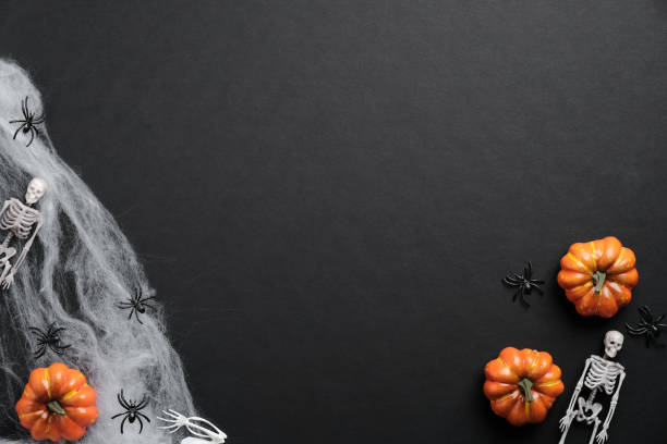 istock Mystery Halloween background with pumpkins, spiderwebs, skeletons, spiders on black table. Flat lay, top view, copy space. 1277764385