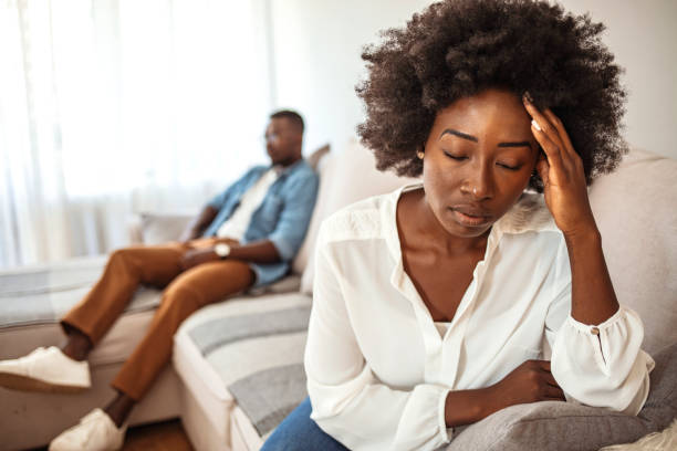 Conflicts in Marriage Unhappy Couple After an Argument in the Living Room at Home. Sad Pensive Young Girl Thinking of Relationships Problems Sitting on Sofa With Offended Boyfriend, Conflicts in Marriage, relationship difficulties stock pictures, royalty-free photos & images