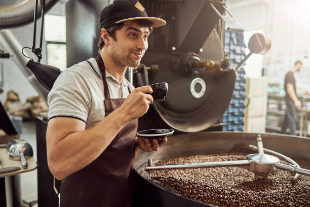 istock Cheerful man roaster drinking coffee near coffee roasting machine 1277765702