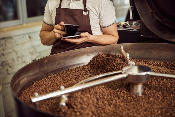 istock Male worker with hot drink standing by coffee roasting machine 1277765709