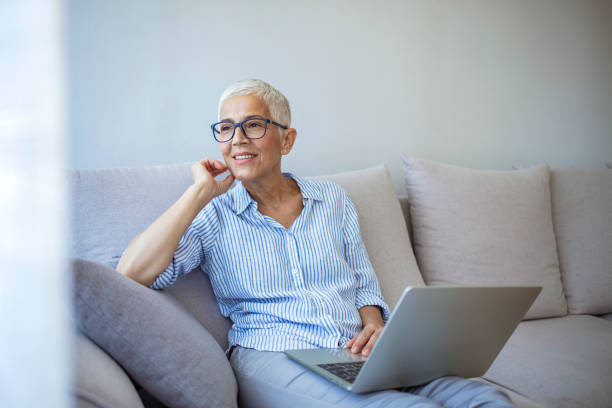 istock Beautiful mature woman sitting on couch and using laptop 1277767265