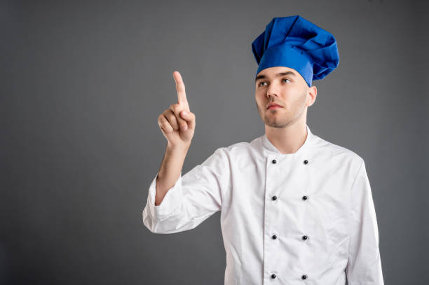 istock Young male dressed in a white chef suit presses a virtual button 1277769157