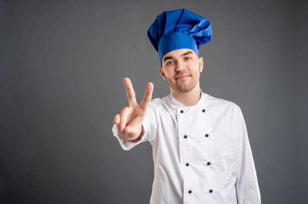 istock Young male dressed in a white chef suit showing victory 1277770059