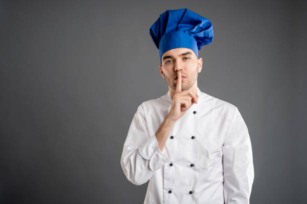 istock Young male dressed in a white chef suit showing shh gesture 1277770163