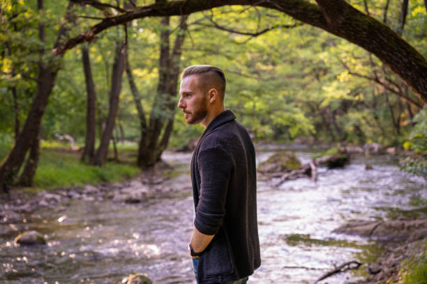 Young fashionable guy posing for a photo in nature Young fashionable guy posing for a photo in nature half shaved hairstyle stock pictures, royalty-free photos & images