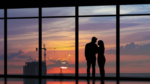 The young couple stand near the windows on the building background. time lapse