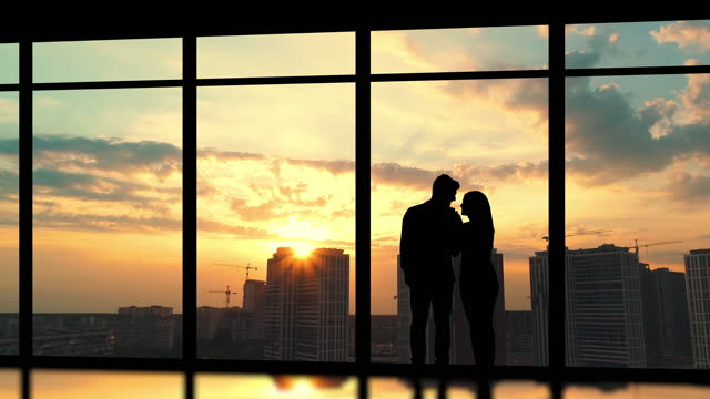 The young couple stand near the windows on the building background