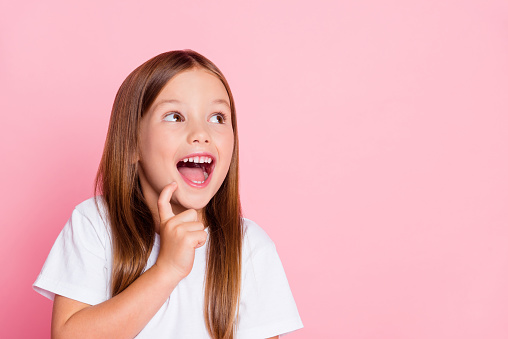 Close-up portrait of a curious ecstatic cheerful cheery girl imagination fantasizing copy empty blank space isolated over pink pastel color background