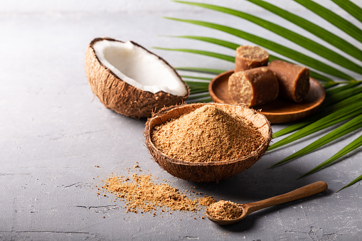 Granular and block shape of organic brown palm sugar or coconut sugar made from coconut juice on grey concrete background with copyspace.