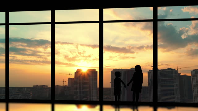 The two kids stand near the big windows on the building background