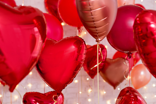 Fondo del día de San Valentín - primer plano de globos rojos en forma de corazón de lámina sobre la pared de ladrillo photo