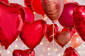 Valentine's day background - close up of red foil heart shaped balloons over brick wall