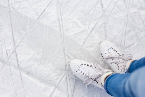 close up top view of legs in skates and copy space over white scratched ice at rink stock photo