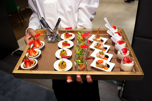 Waiter serving canape selection on slate platter