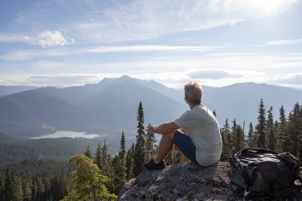 istock Male hiker relaxes on rock overlook, above valley 1277782752