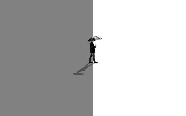 Monochromatic shot of a man standing between two different colors black and white going towards the light.