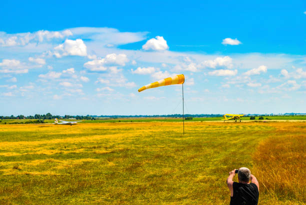 男は青空でウィンドックと飛行場を撮影 - windsock weather airplane people ストックフォトと画像