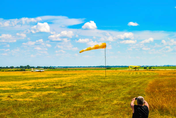남자는 푸른 하늘에 의해 윈드삭과 비행장을 촬영 - windsock weather airplane people 뉴스 사진 이미지