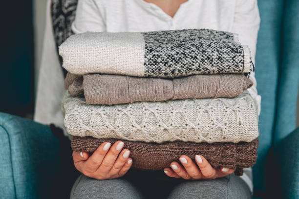istock Female hands hold a stack of warm knitted sweaters 1277788009