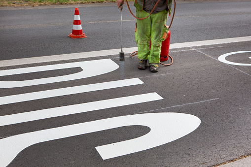 Unrecognisable road workers applying a bus lane pictogram on the street in the city center of Wiesbaden