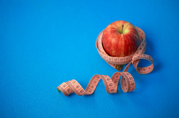 건강을 위해 하루에 한 사과. 파란색 배경에 센티미터 테이프가있는 빨간 사과. - snail escargot animal speed 뉴스 사진 이미지