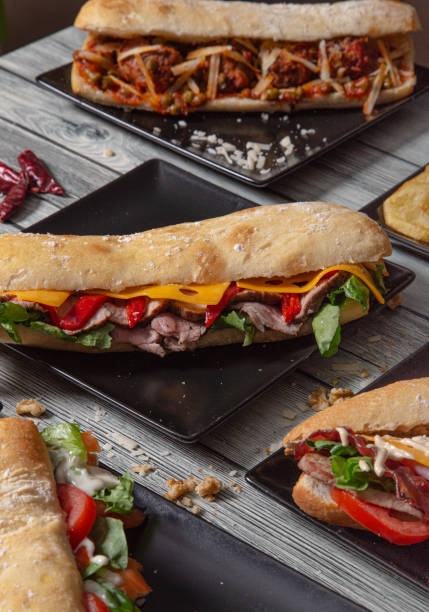 istock Baguette sandwiches with various ingredients served in ceramic plates on wooden table. Image isolated. Variety of sandwiches 1277791061