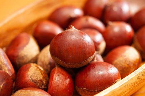 Closeup image of bunch of chestnuts in a wooden bowl.  Taste of autumn.