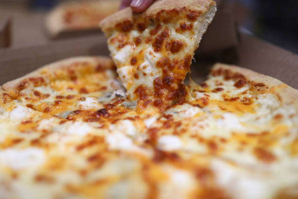Ultra Close-Up Wide Angle Macro Shot of Greasy Melted Cheese on Delicious Steaming Hot Deep Dish Pepperoni Pizza Fresh Out Of The Oven on a Cooling Rack Under a Heat Lamp