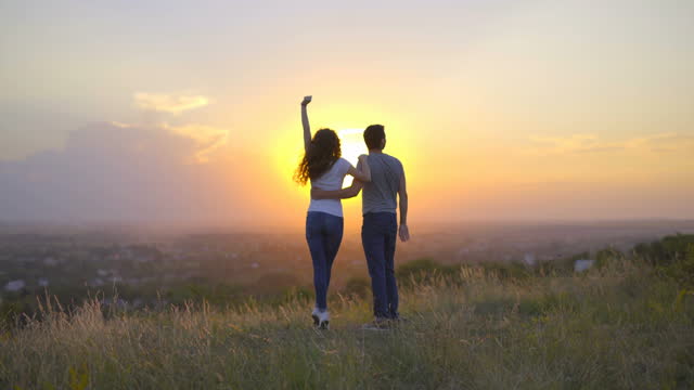 The couple play on the background of the sunset. Wide angle. Real time capture