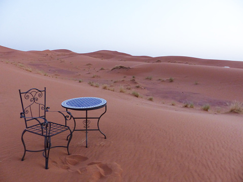 Chairs and table in the middle of the dunes of the Erg Chebbi desert, Merzouga, Sahara, Morocco.