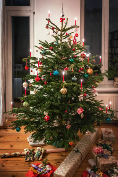 gift boxes under the festive decorated fir tree with candles burning at christmas eve