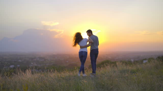 The couple play on the background of the sunset. Wide angle. Real time capture
