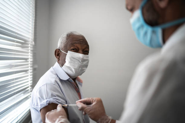 얼굴 마스크를 사용하여 환자의 팔에 백신을 적용하는 간호사 - applied science 뉴스 사진 이미지