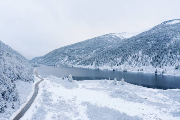 istock First snow in autumn covered mountain valley with lake reflection and road 1277812064