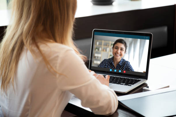 businesswoman having distant negotiations using video conference application on pc - looking in camera imagens e fotografias de stock