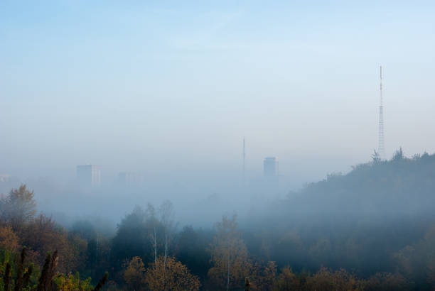 City view through the ravine in fog. Autumn dawn near small river.