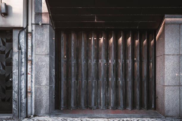 Garage or entrance closed metal gates texture with brown vertical fanfold lines of the door; front view of an accordion-folded painted door of a big gate on the street, common in Lisbon, Portugal