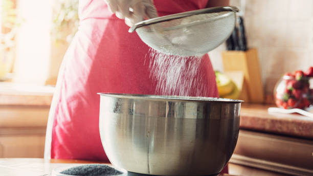 女性は台所でケーキを準備する前にふるいを通して小麦粉をふるいにかけます。 - bread bakery women cake ストックフォトと画像
